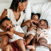 a family playing on a bed and laughing