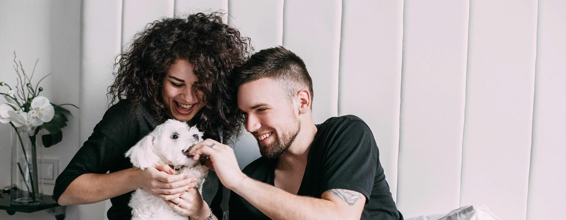 a man and woman sitting on a bed holding a dog