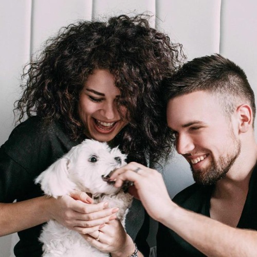 a man and woman sitting on a bed holding a dog